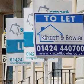 Four "TO LET" signs hung up outside four properties that are next to each other.