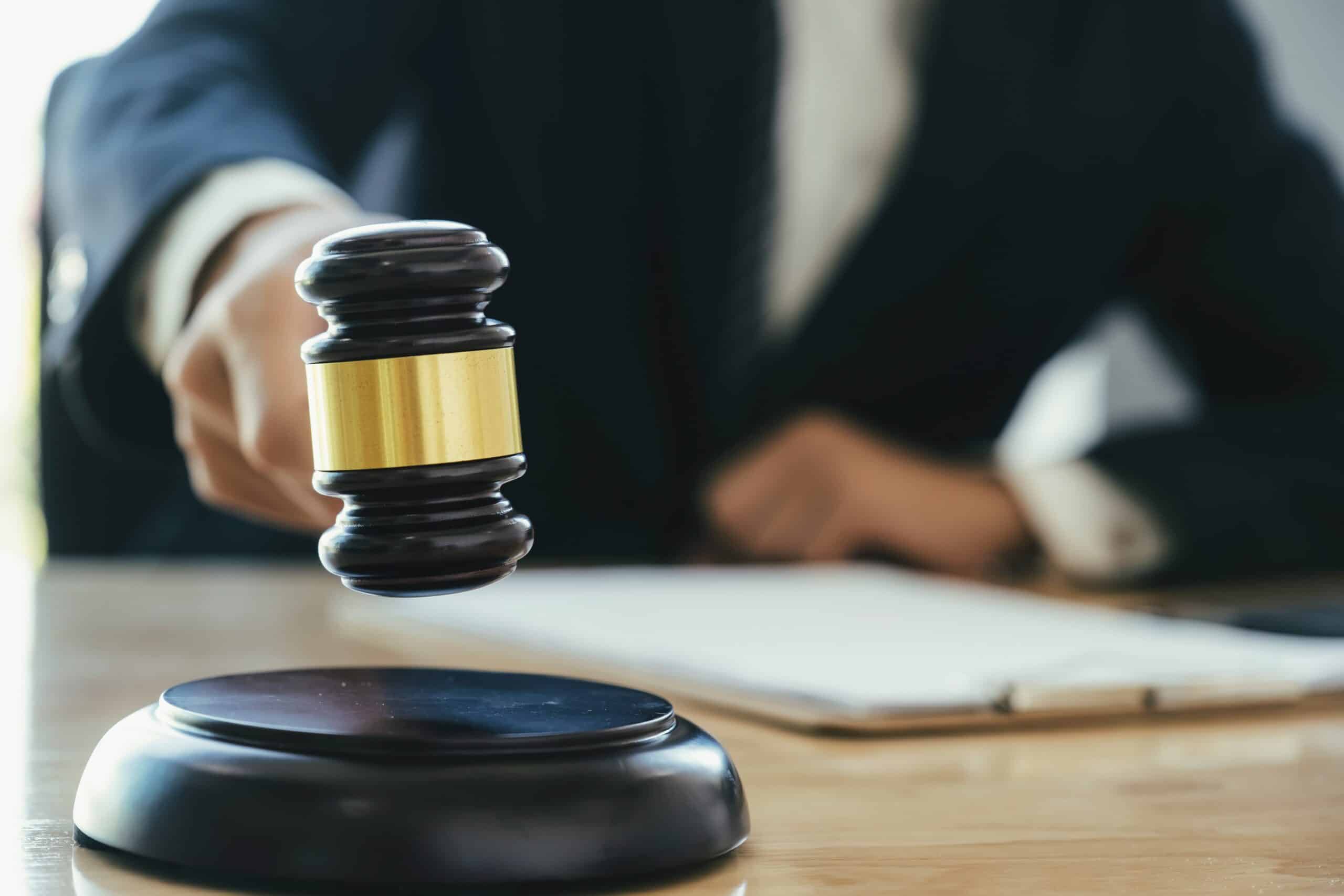 A hand holding a gavel over a wooden block